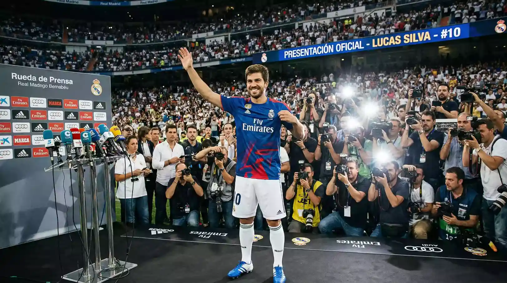 Jugador de futbol posando con una camiseta nueva durante una presentacion oficial en un estadio