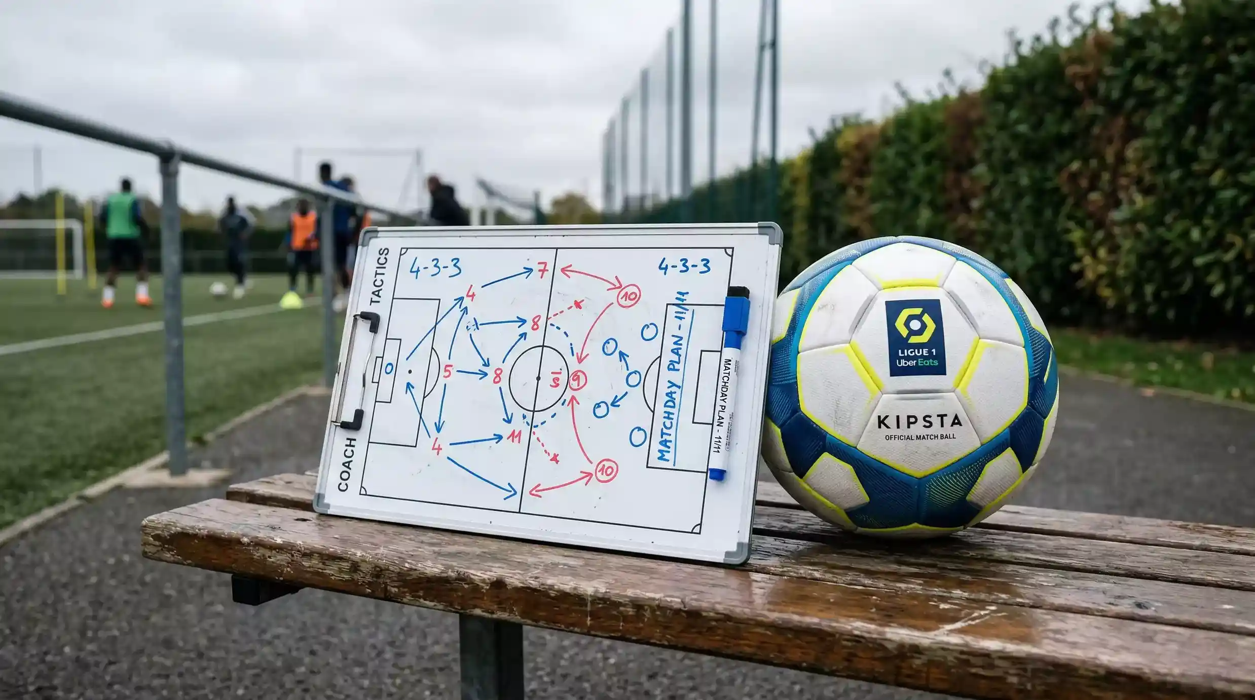 Pizarra tactica de futbol con lineas y numeros dibujados junto a un balon de la Ligue 1